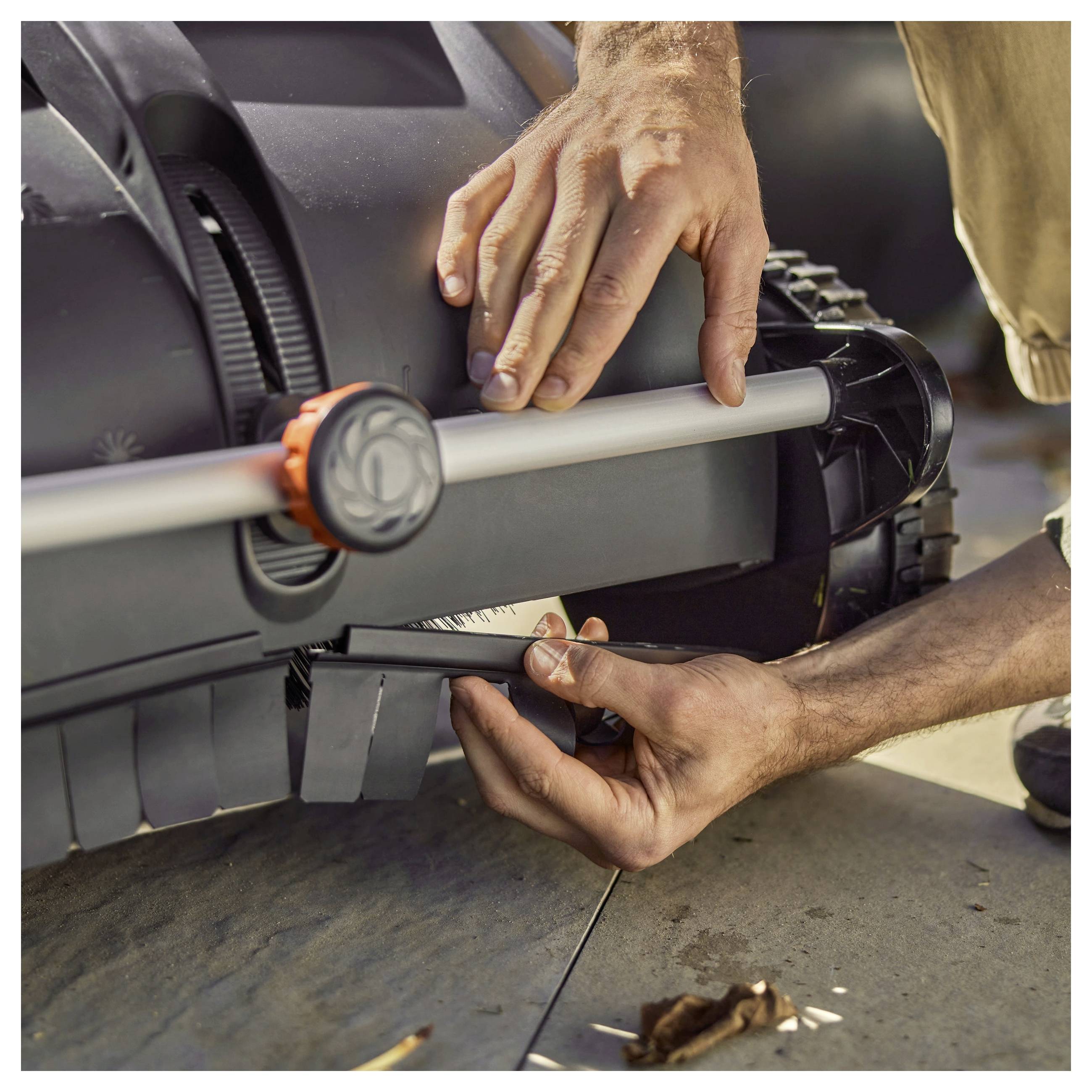 A person adjusts the settings on a lawn mower, focusing on the handle area, indicating maintenance or preparation for use.