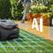 A robotic lawnmower navigates a yard with AI technology, avoiding obstacles. A grid overlays grass, highlighting its path planning feature.