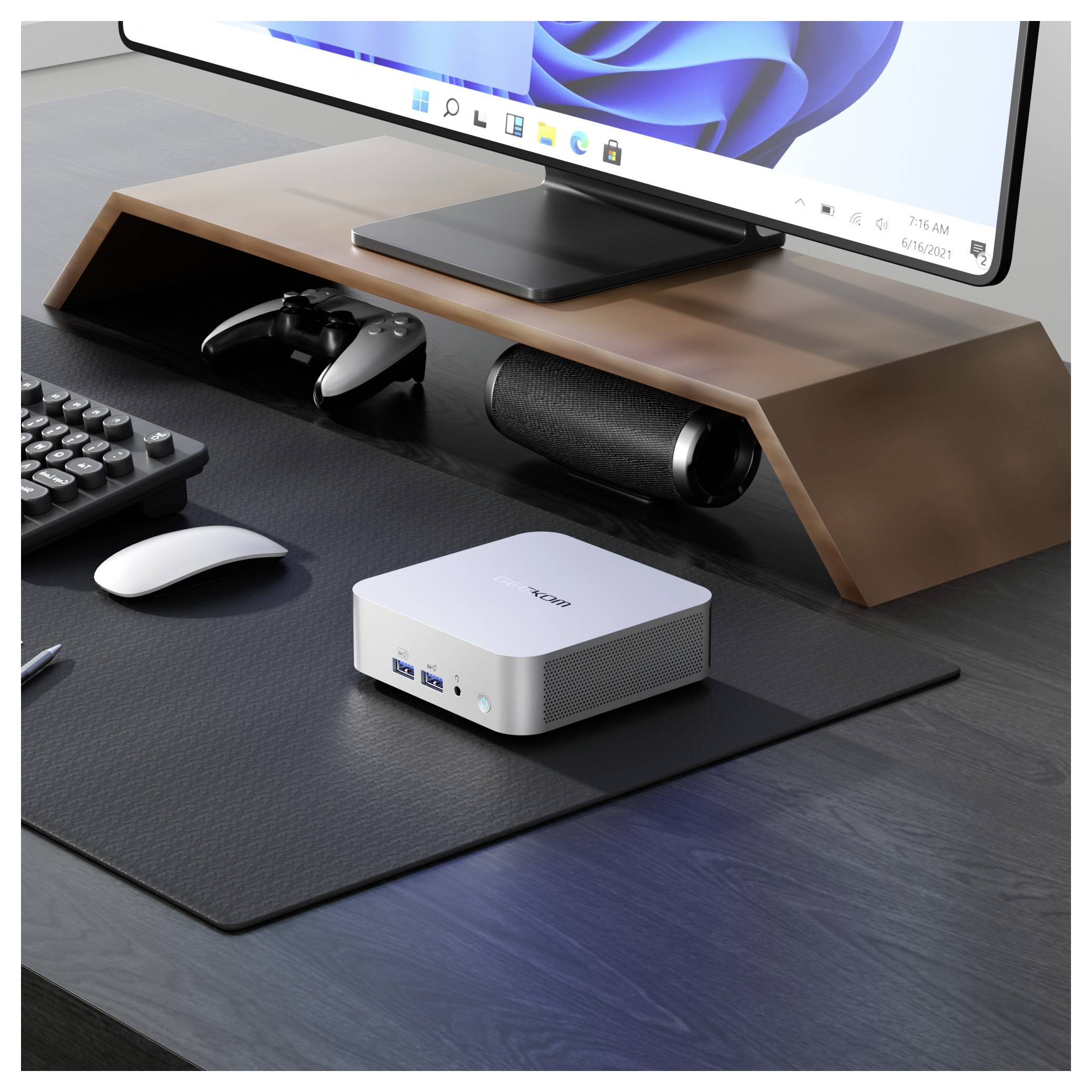 A minimalist workspace featuring a monitor on a wooden stand, a compact computer, a keyboard, mouse, and a game controller.