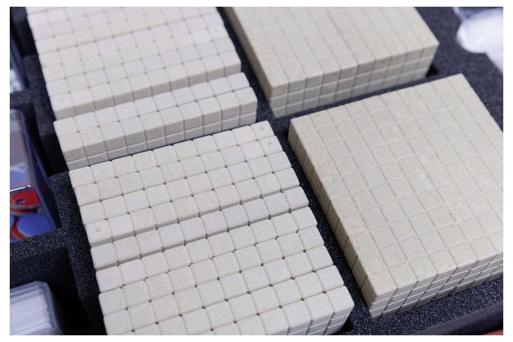 Wooden blocks grouped in sets on a foam tray, resembling place value blocks used for mathematical teaching or demonstrations.