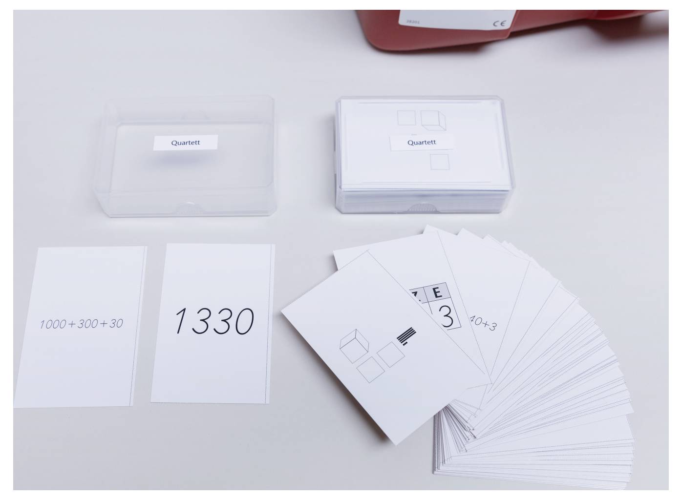 'Quartett' card game with math equations and answers. One card shows '1000+300+30', the answer card reads '1330'.