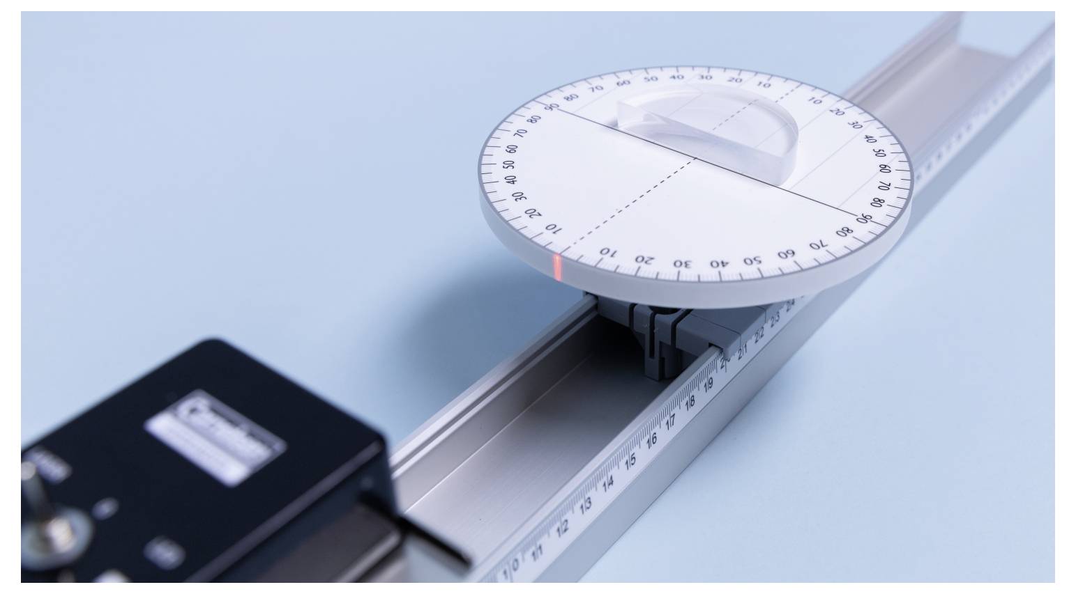 'Plastic Dial' protractor on a metal rail against a blue background, marked with degrees and aligned at 90 degrees.