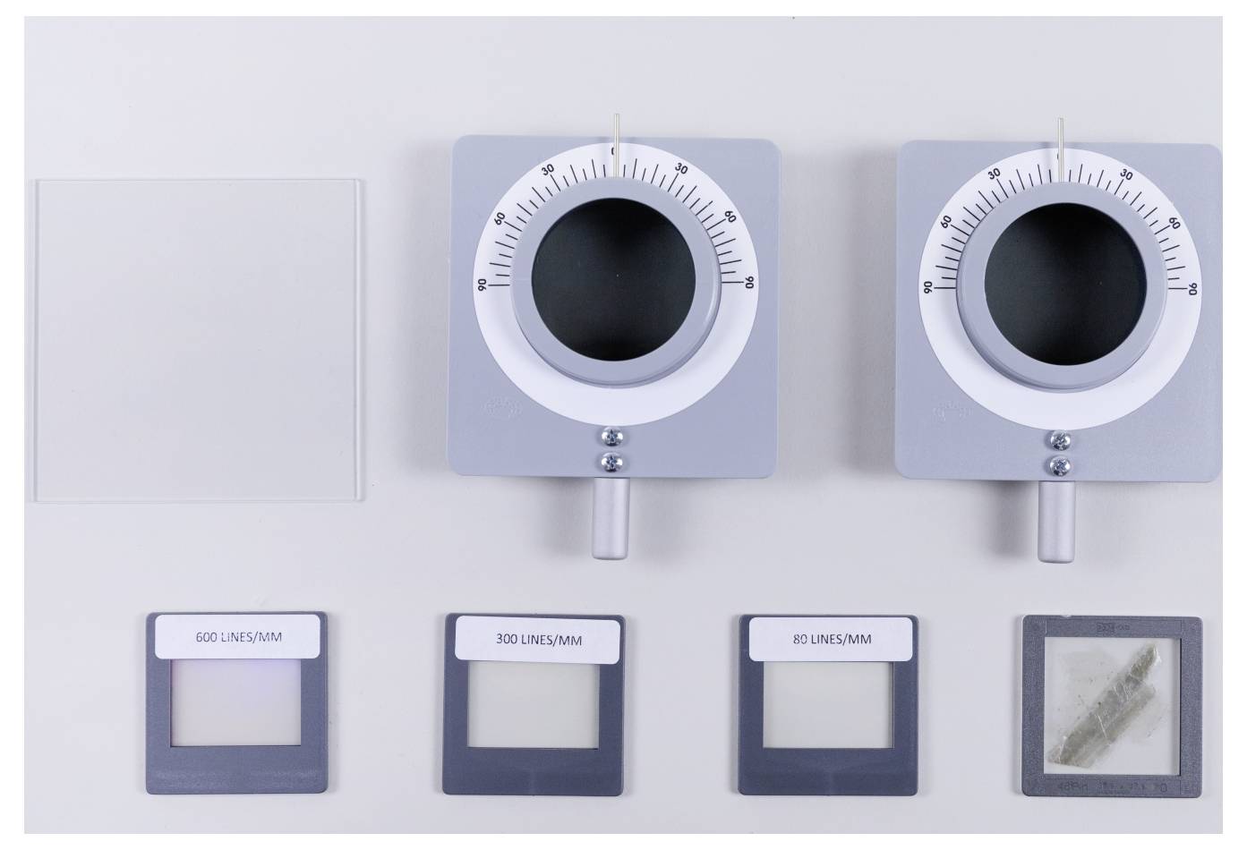 'Two circular dials with black centers, labeled at top. Below, four slides: 600 lines/mm, 300 lines/mm, 60 lines/mm, and a feather.'
