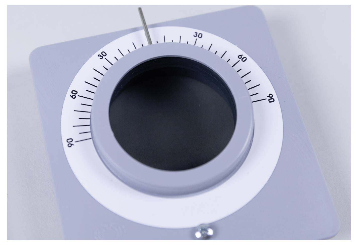 A close-up image of a round, gray dial thermostat set to approximately 50 degrees. The dial is mounted on a square, light gray background.