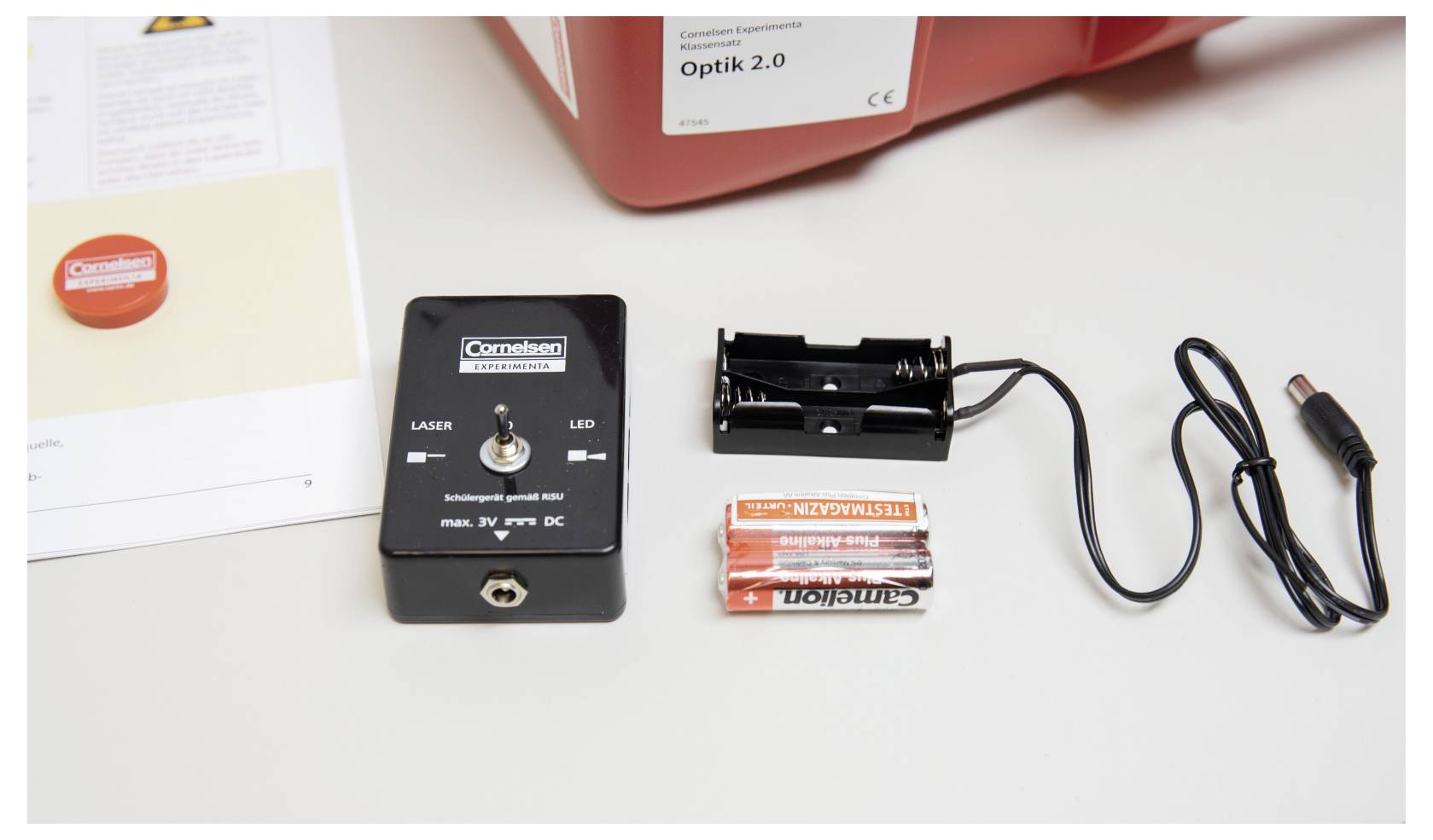 Components of an optical experiment kit: a laser module, battery holder with connected wire, batteries, and an instruction manual.