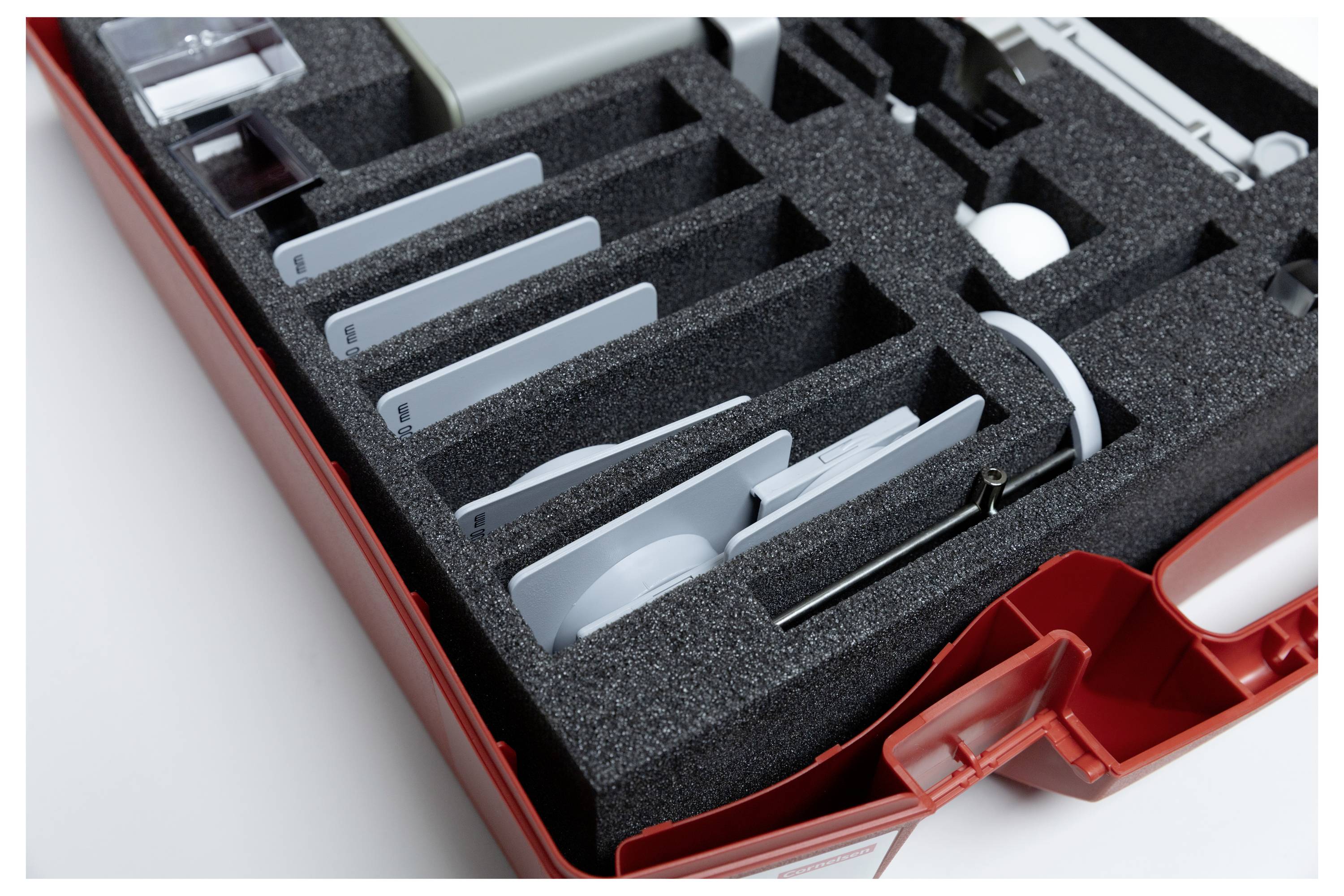 Red tool case with foam insert organizing various white and metallic tools and components, indicating preparedness and organization.