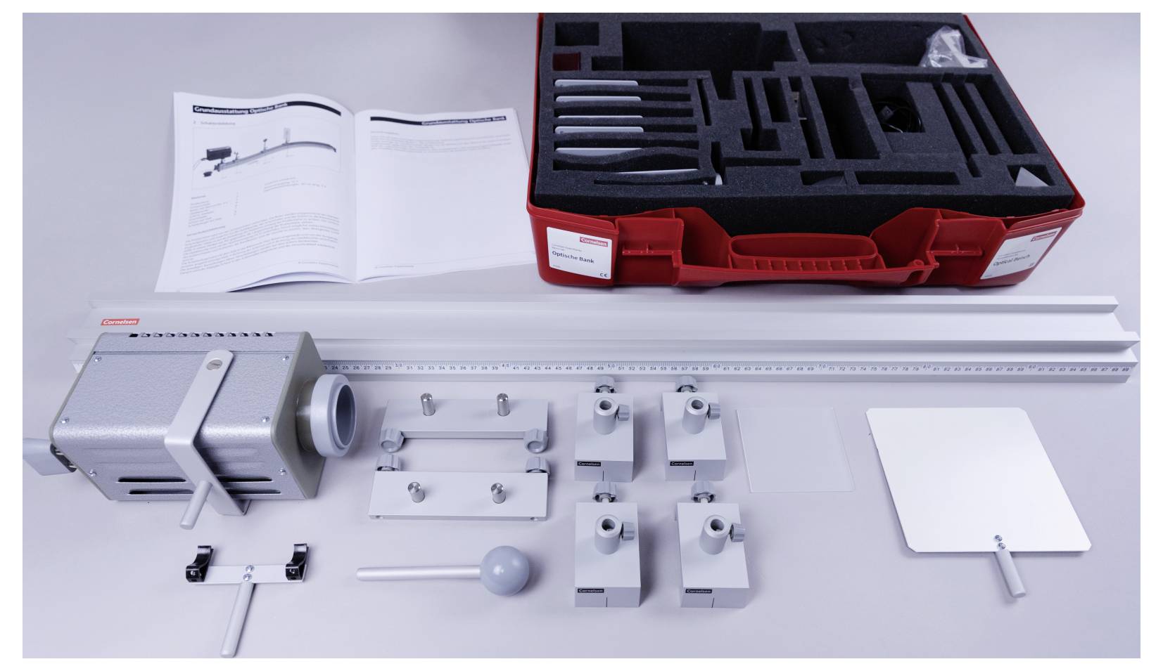 A red tool kit with foam compartments containing various metal and plastic components, along with instructions and a metal ruler.