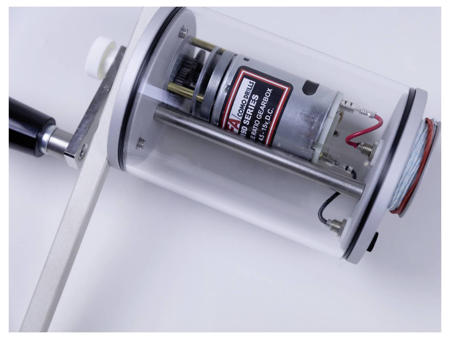 A close-up image of a cylindrical motor encased in clear plastic, featuring a red and white label with technical information.