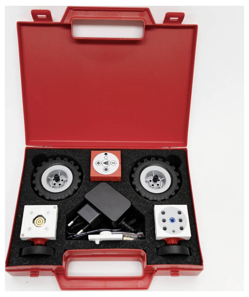 A red tool case contains various mechanical components, gears, and an adaptor, organized neatly within a custom foam insert.