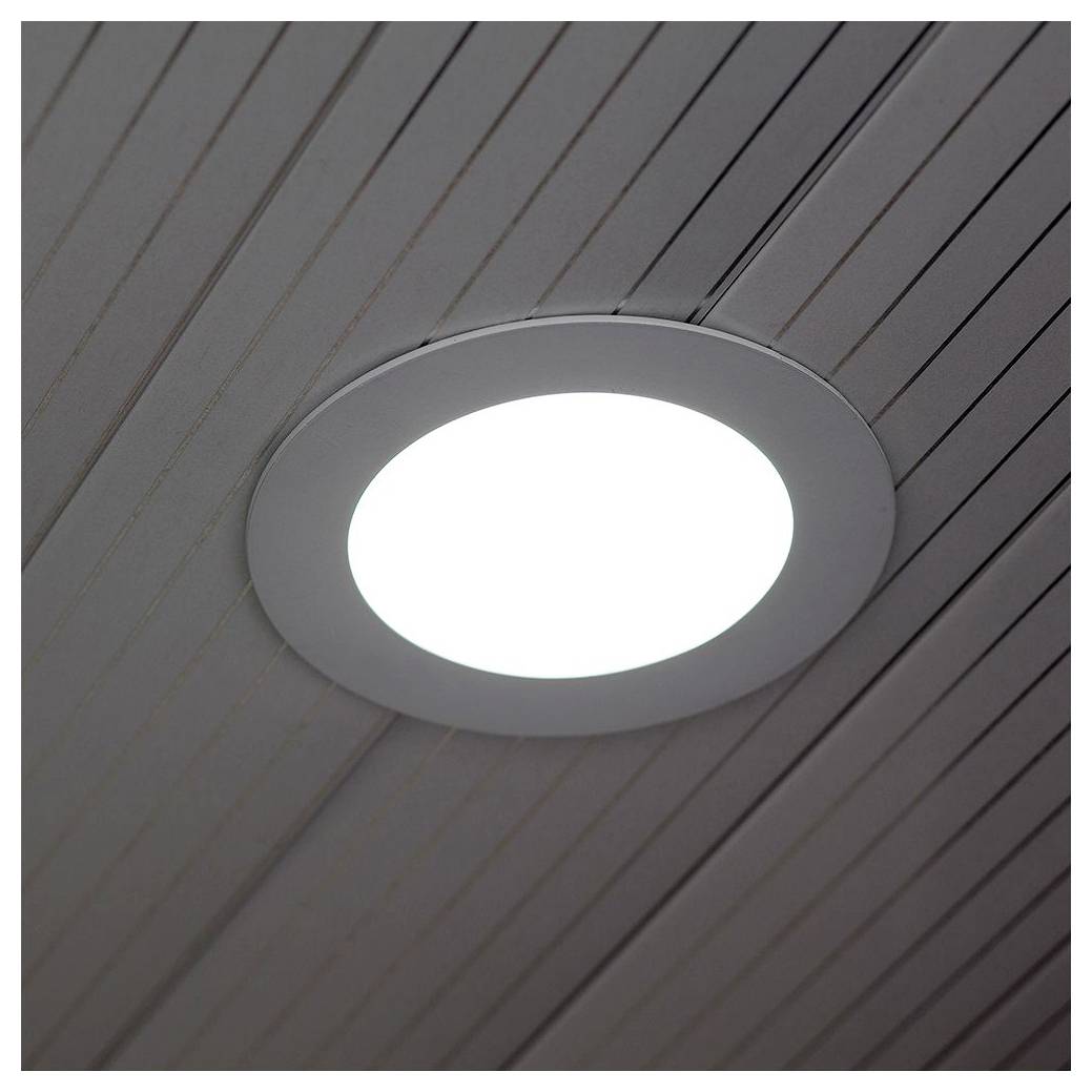 A round ceiling light fixture is turned on, emitting bright white light against a striped wooden ceiling background.