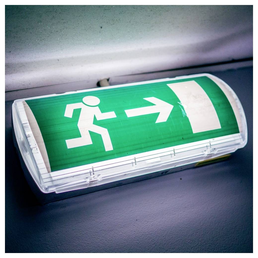 'Emergency exit sign with a running figure pointing right towards a rectangle, indicating the direction to safety.'