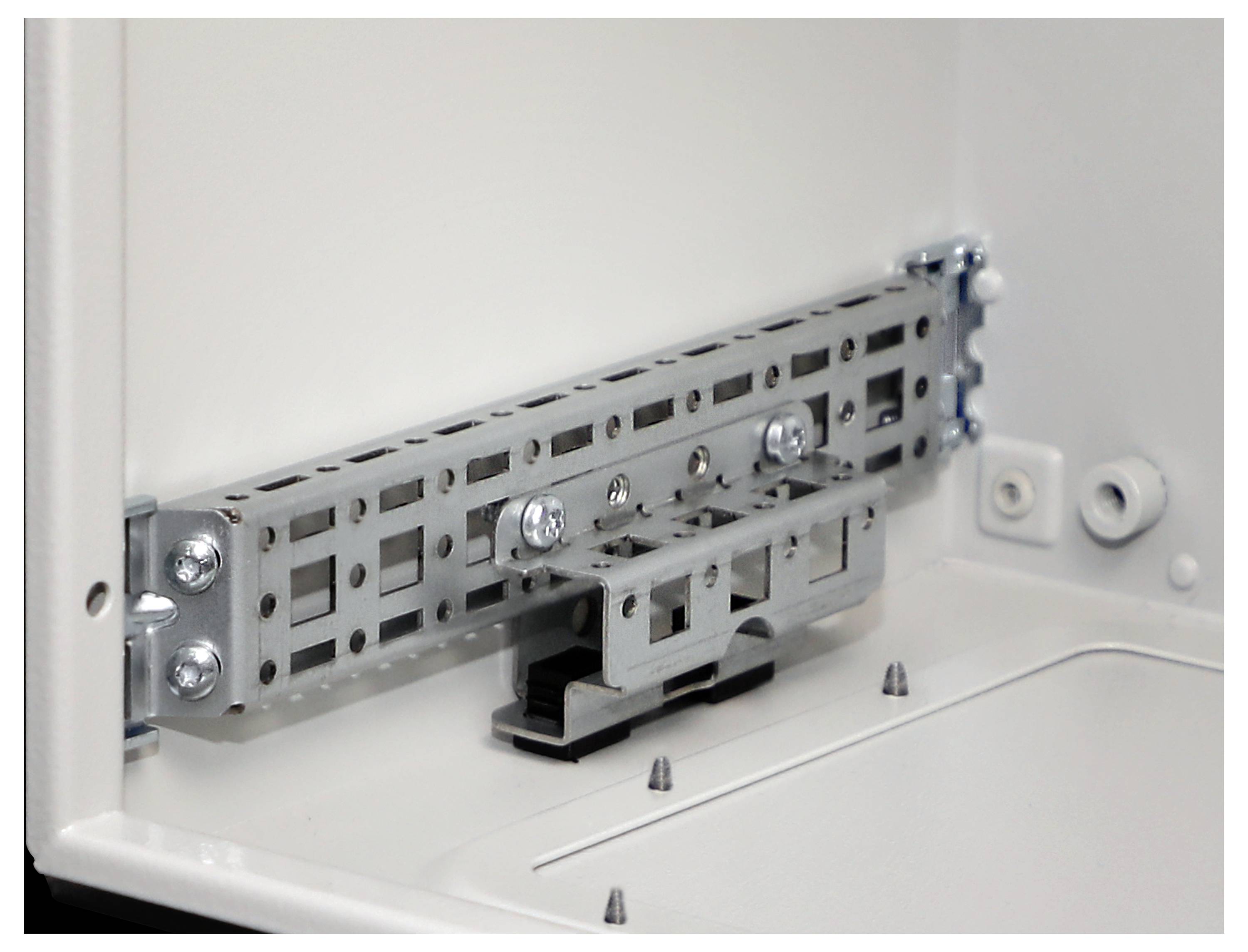 An electrical panel interior showing a metallic mounting bracket attached with screws. The panel is open, revealing its structure.