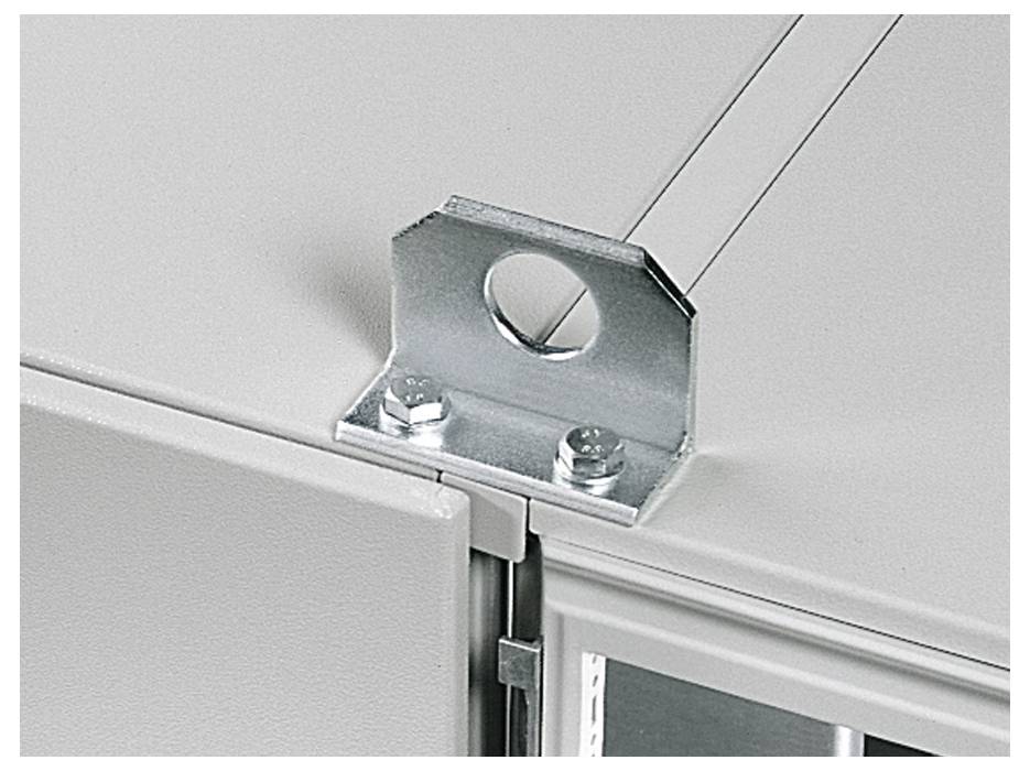 A close-up of a metal mounting bracket with a circular hole, attached to a corner of a light-colored cabinet.