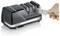 A person is sharpening a knife using a black electric sharpener with two stages, labeled '1' and '2', on a countertop.