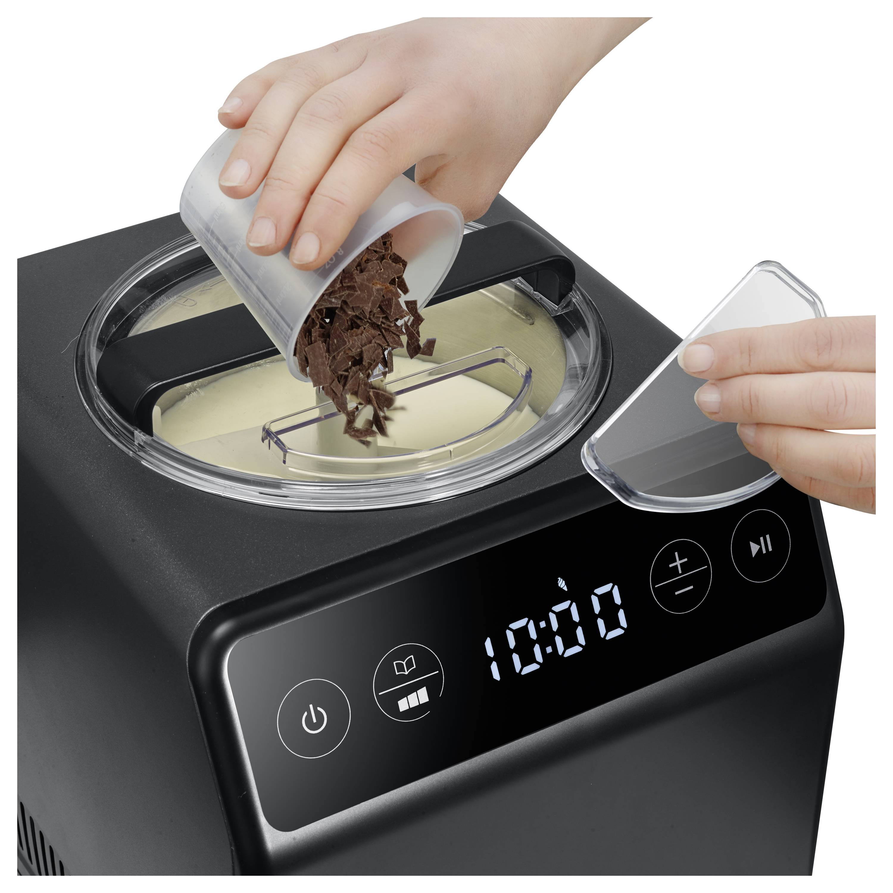 Hand pours chocolate chunks into an ice cream maker, partially covered by a clear lid; digital display shows '10:00'.