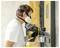 A person wearing a respirator mask and gloves uses a spray paint gun to apply paint to a masked-off door.