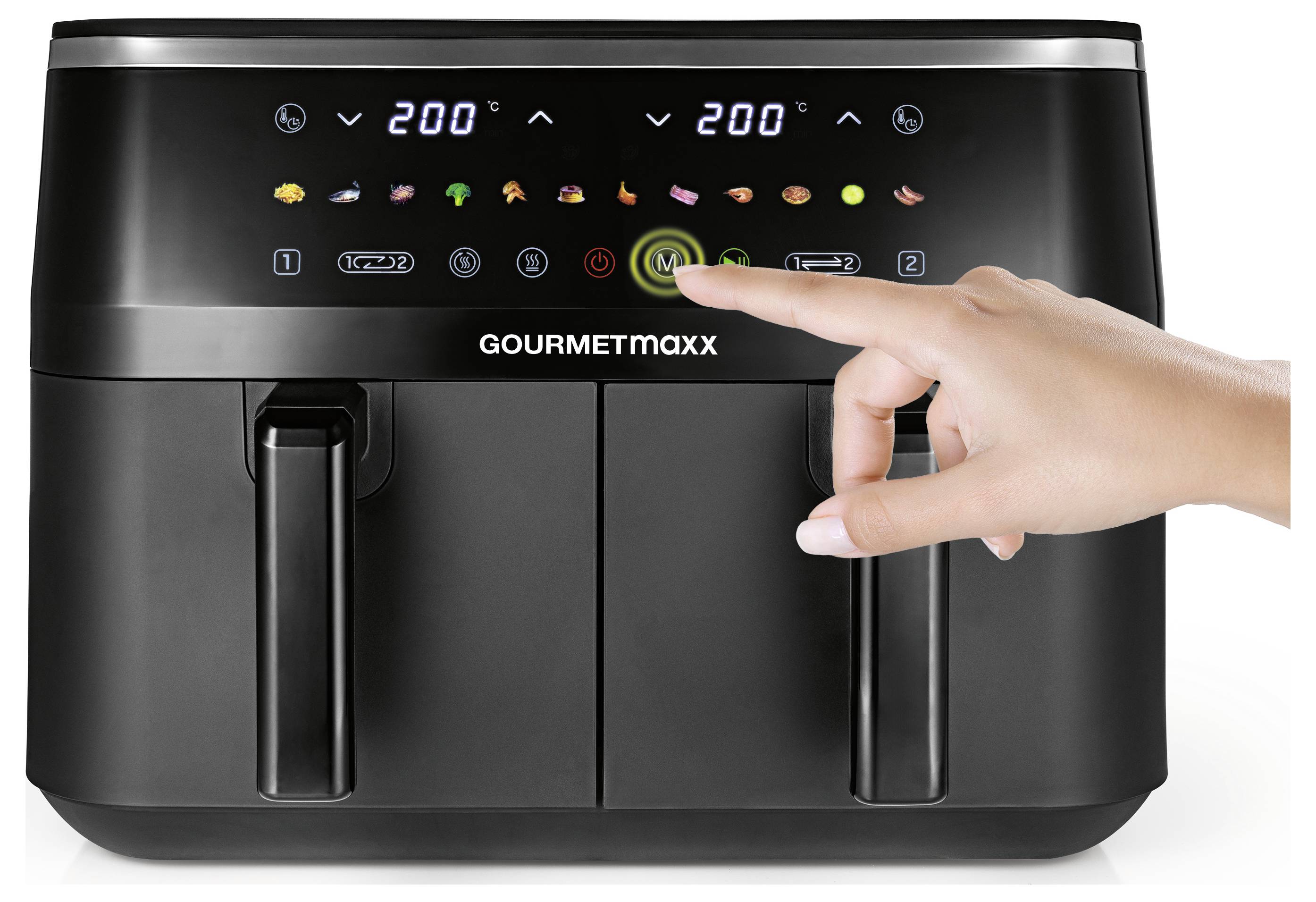 A dual-compartment air fryer with a digital display showing temperature settings. A hand presses a button to select a cooking mode.