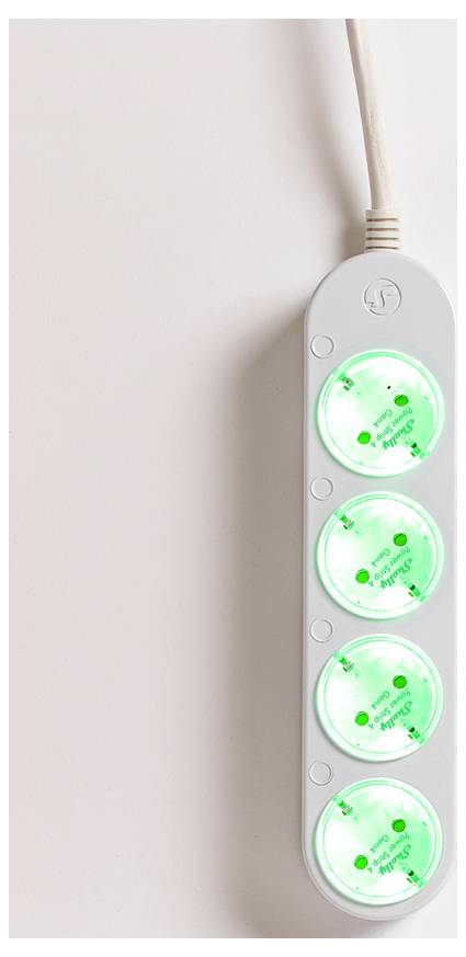A white power strip with four sockets, each illuminated with green light, lies on a light surface.