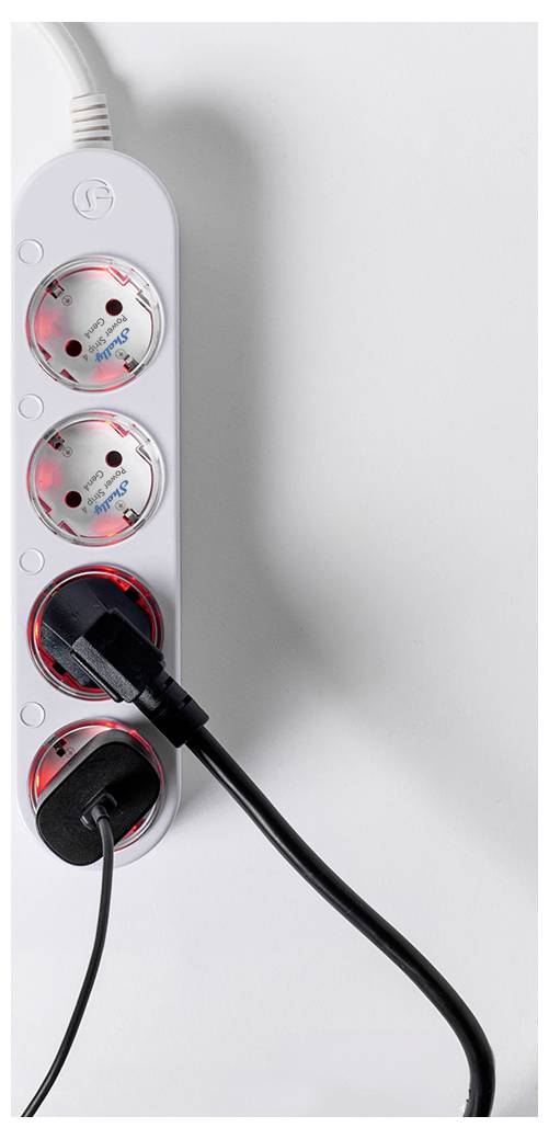 A white power strip with three unused outlets and two plugged-in black power cords against a white background.