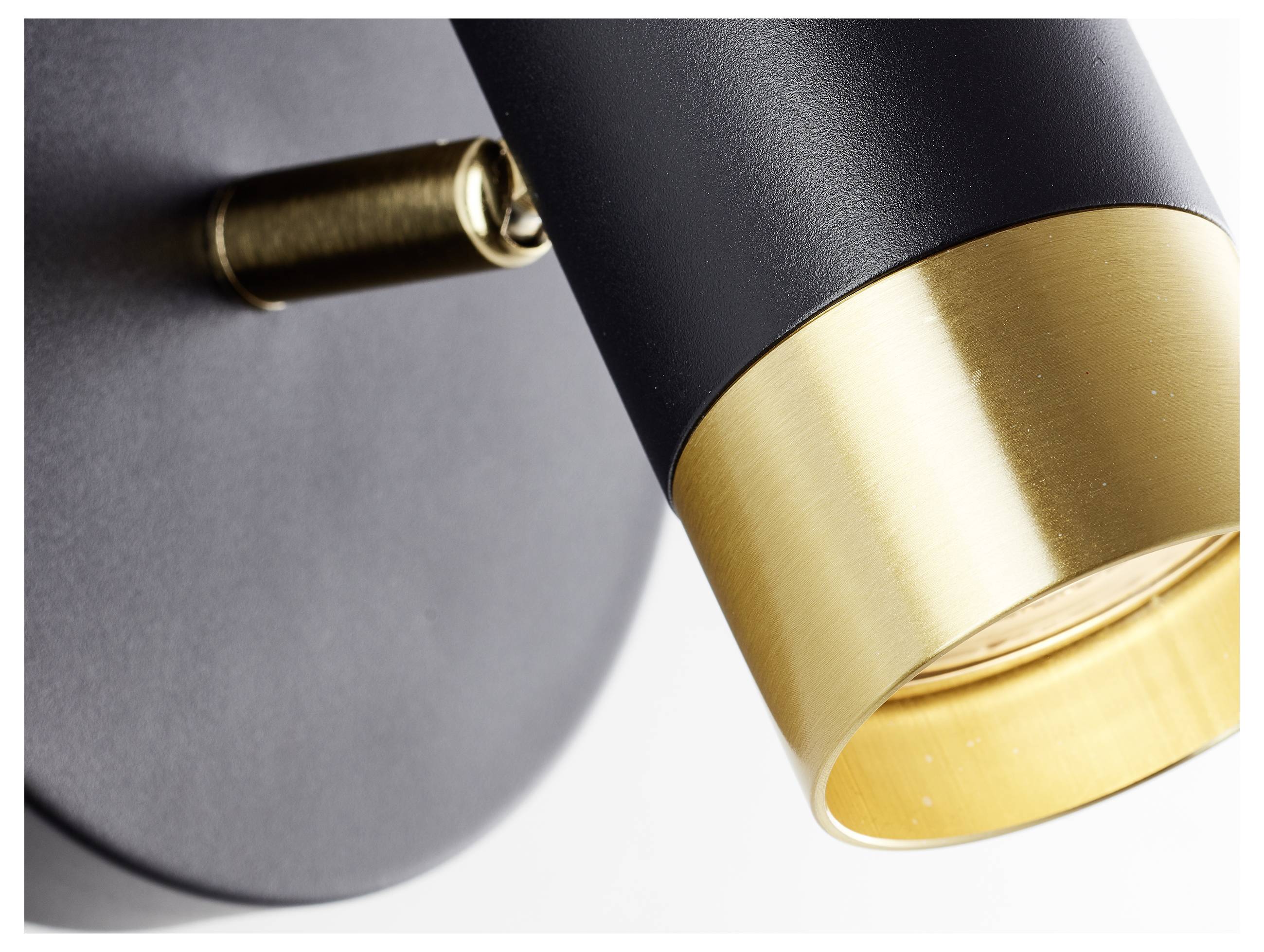 Close-up of a modern light fixture with a black cylindrical body and gold accent near the bulb.