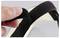 A hand adjusts a black Velcro strap against a light gray background, demonstrating how to secure or release it.
