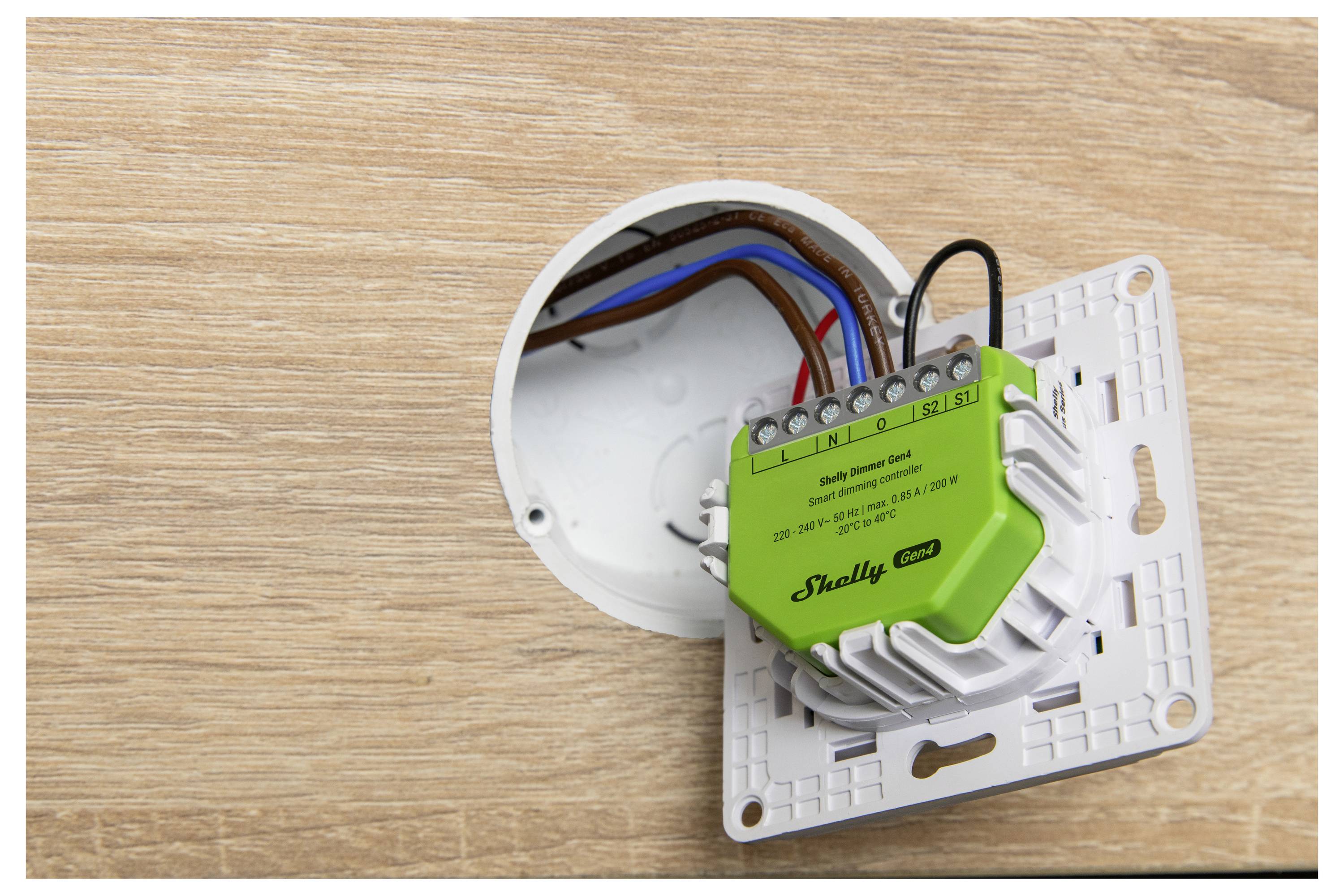 Smart relay device installation inserted into a wall socket, showing connected wires and device labeled 'Shelly 1PM'.