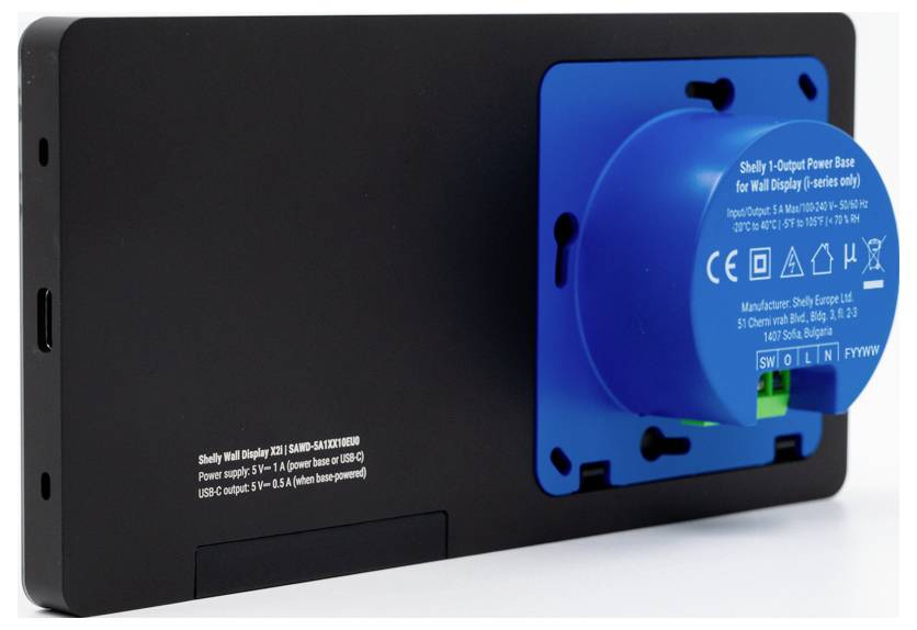 A black wall display with a blue power base attached, labeled 'Shelly 1 Output Power Base for Wall Display,' showing power specifications.