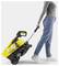 A person pulls a yellow and black portable cleaning device on wheels by its handle.
