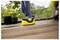 A person uses a yellow power washer to clean a wooden deck, with potted plants visible in the background.