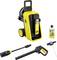 Yellow and black pressure washer with hose reel, spray gun, lance, and detergent bottle, arranged on a white background.