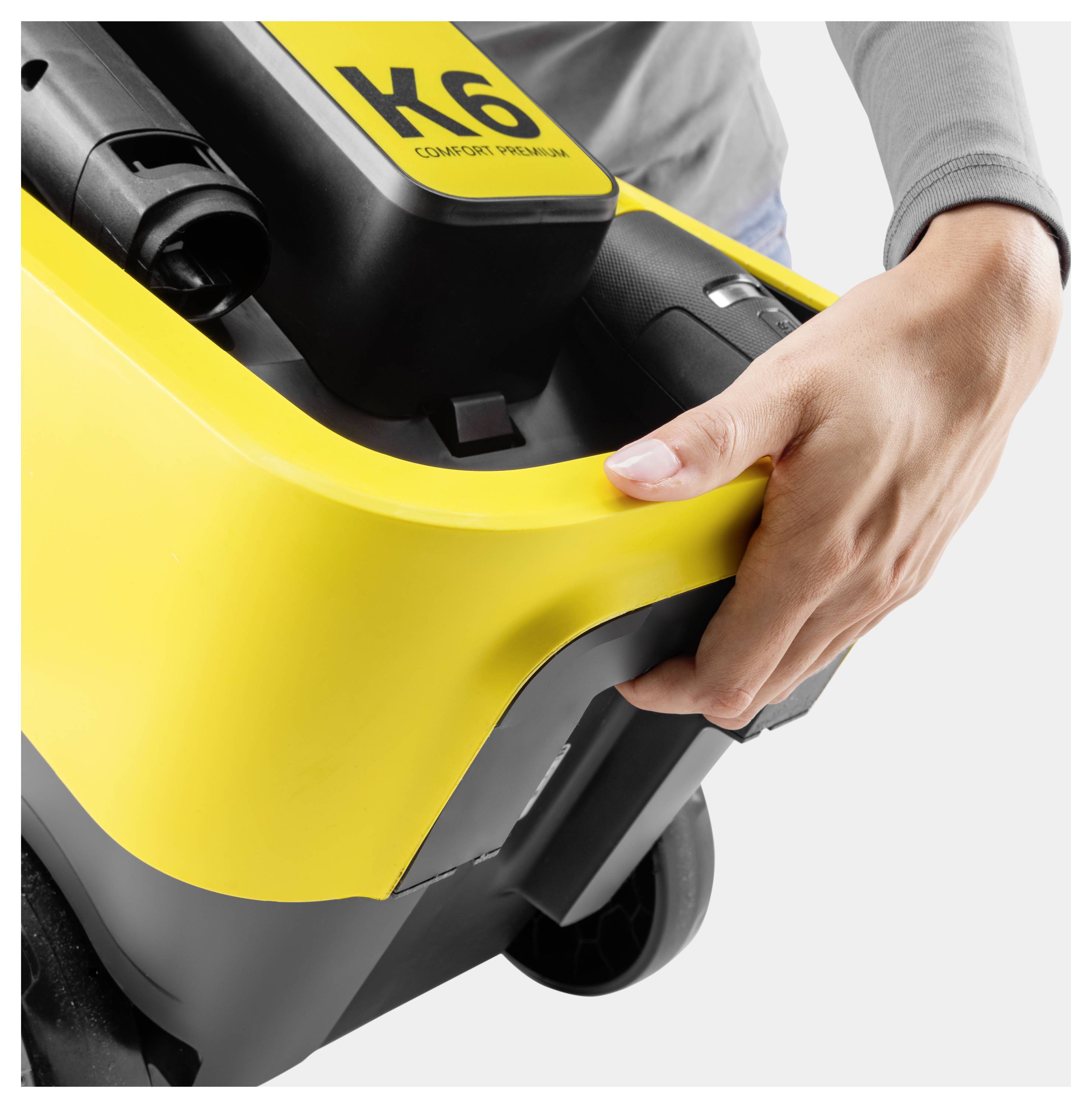 A person is holding the handle of a yellow and black K6 pressure washer, highlighting its portability and design.