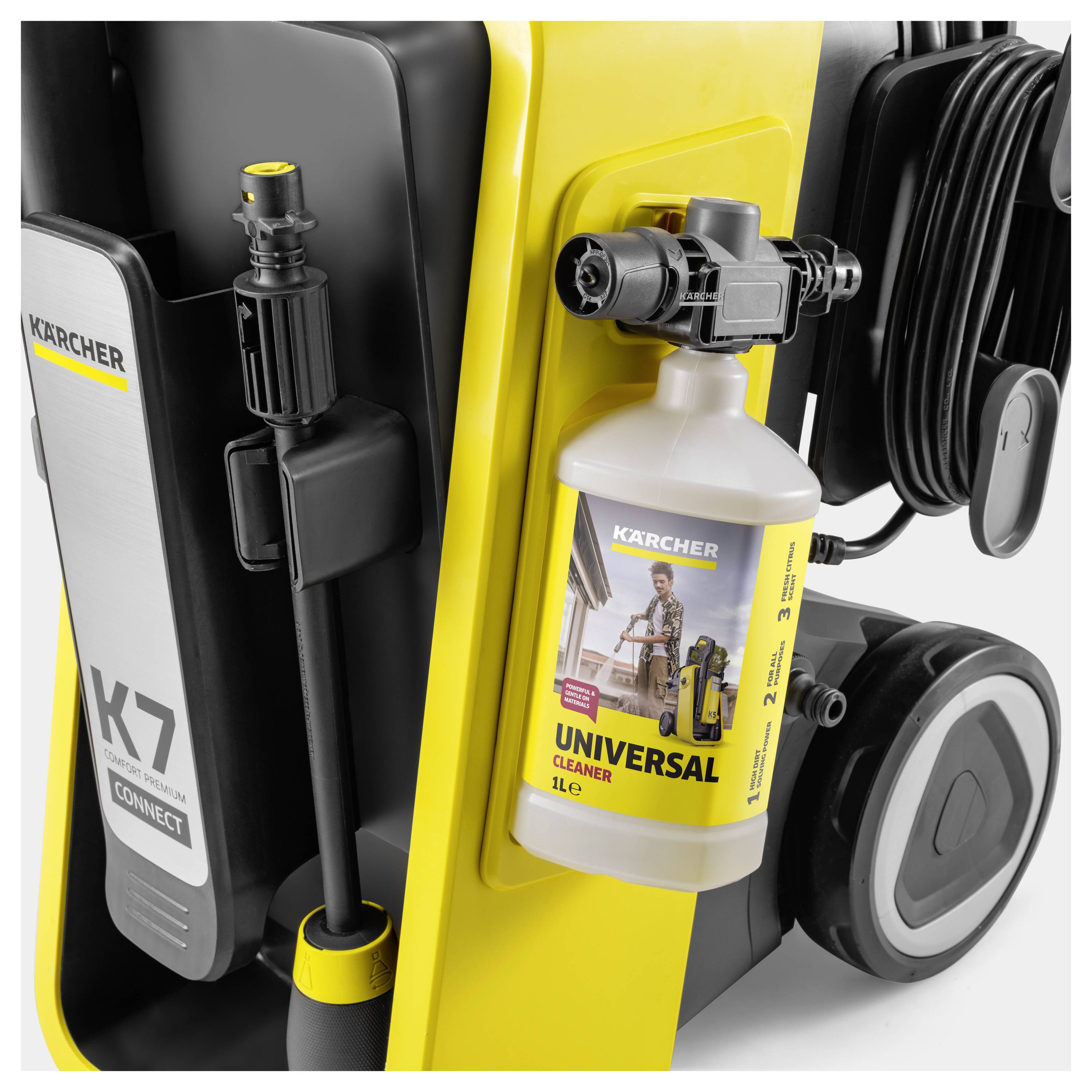 'Close-up of a yellow Karcher pressure washer with attached universal cleaner bottle, labeled for cleaning various surfaces.'