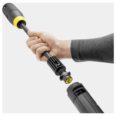 'Hand connecting a lance to a black and yellow pressure washer, demonstrating assembly or usage of the cleaning device.'