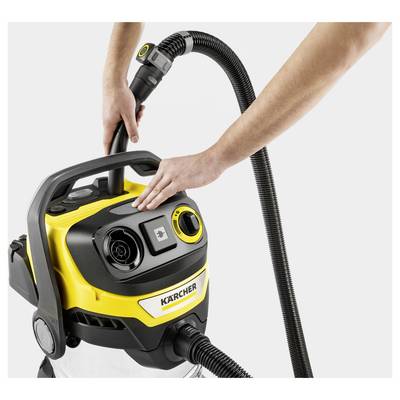 Person using a yellow and black Kärcher vacuum cleaner, adjusting controls on top while holding the hose.