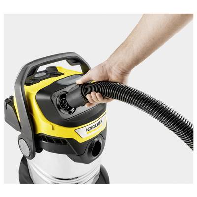 A person attaches a hose to a yellow and black vacuum cleaner labeled 'Karcher', highlighting the vacuum's connectivity feature.