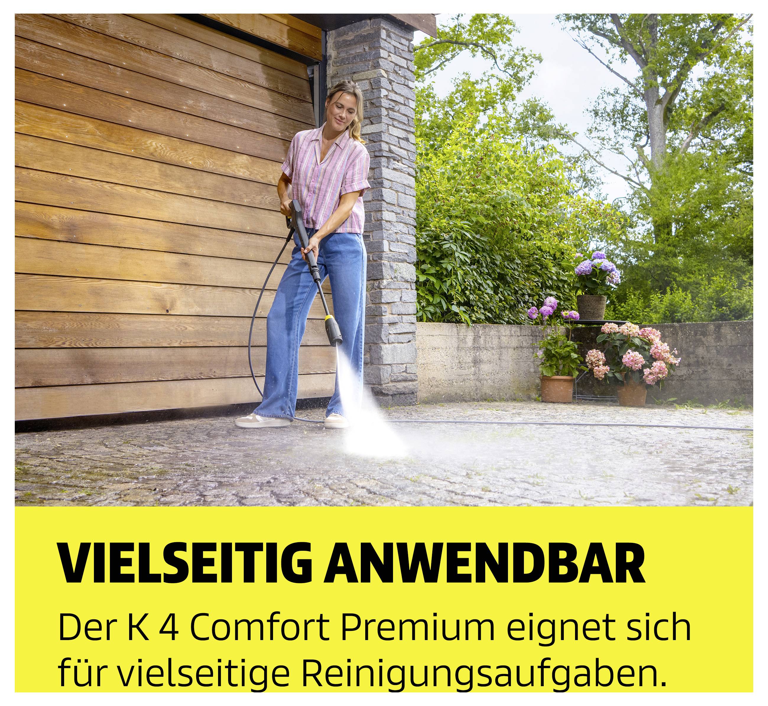 Woman cleaning a courtyard in front of a garage with a high-pressure cleaner; Text: 'VERSATILE APPLICATION' and 'The K 4 Comfort Premium is suitable for a wide variety of cleaning tasks.'