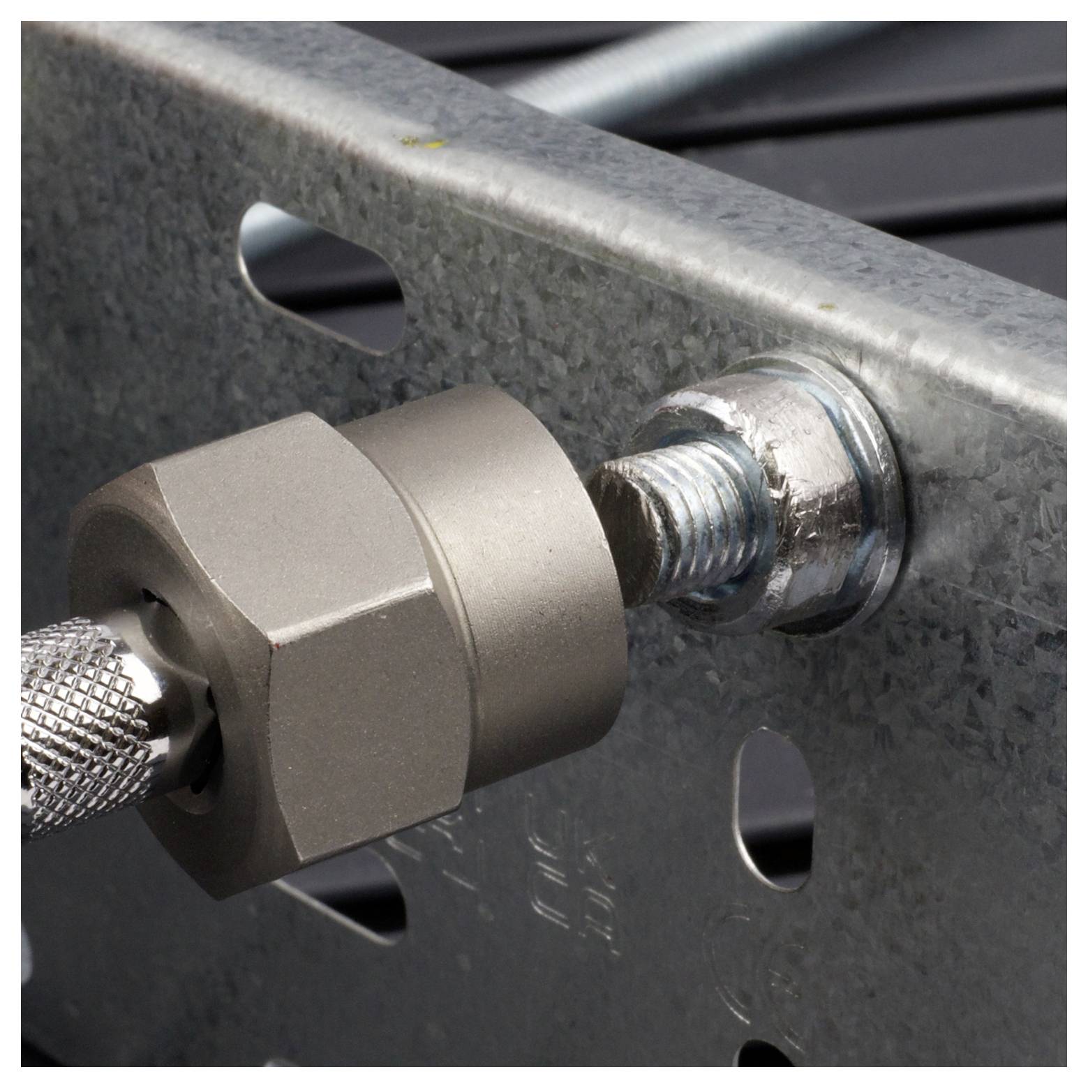 A metal bracket with a hex nut fastened onto a threaded bolt, attached to a perforated metal surface, illustrating mechanical fastening.