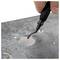 Hand deburring a hole in a metal sheet using a deburring tool to remove rough edges and create a smooth finish.