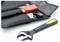 A black adjustable wrench lies beside a black tool bag with pockets, containing a red-handled tool and other metal tools.