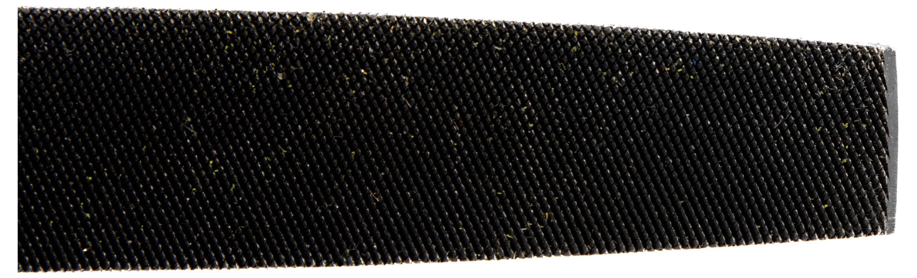 A close-up image of a textured black surface, possibly a coarse file or abrasive tool, showing detailed pattern and material fibers.