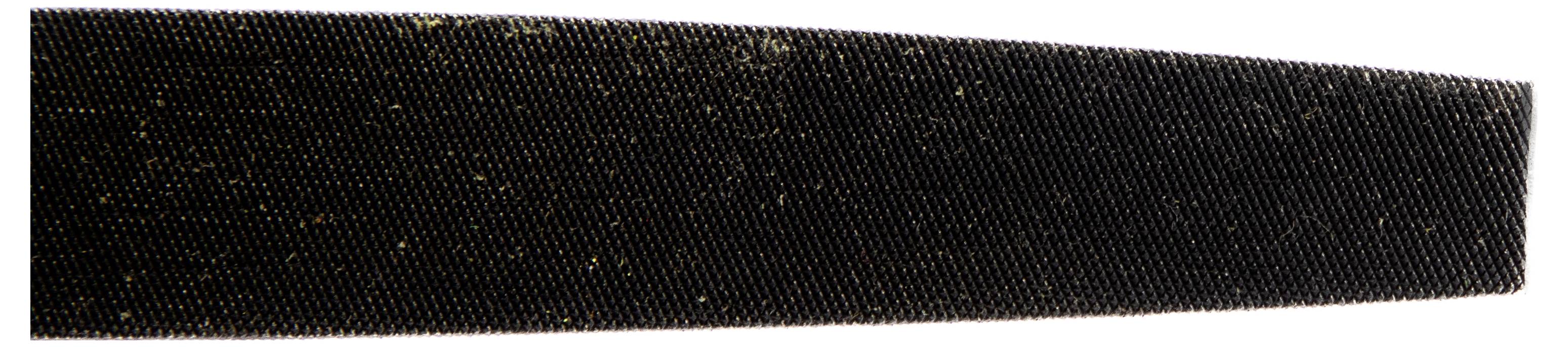 Close-up of a black serrated object, possibly a file or tool, showing fine horizontal ridges and specks of dust on the surface.