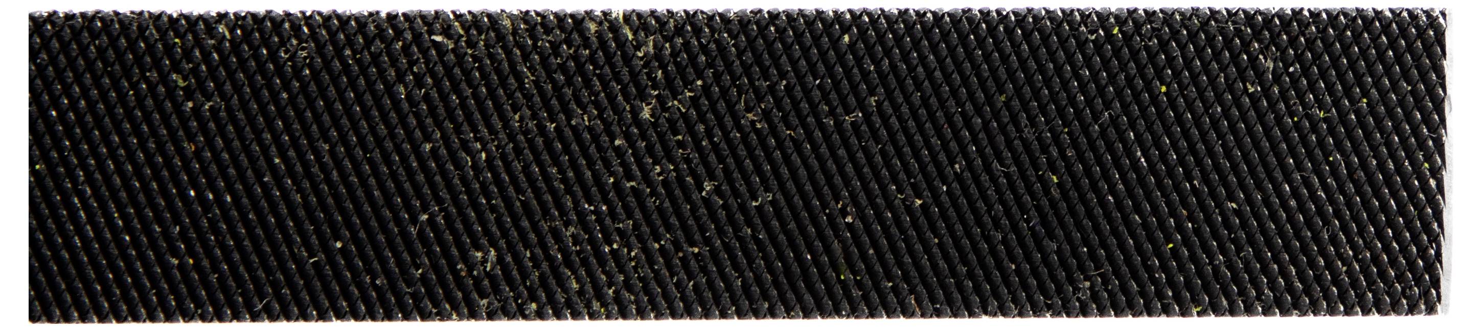 A close-up view of a textured black surface with fibrous debris scattered across it.