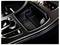 Car center console storage tray with a 12V power outlet and cup holder, shown in a carbon-fiber trim interior.