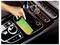 Hand placing a smartphone with 'NBA' on a car’s wireless charging pad beside the center console controls.