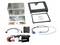 Car stereo installation kit with metal mounting brackets, dash trim, wiring harnesses, connector adapters, and antenna adapter parts laid out on a white background.