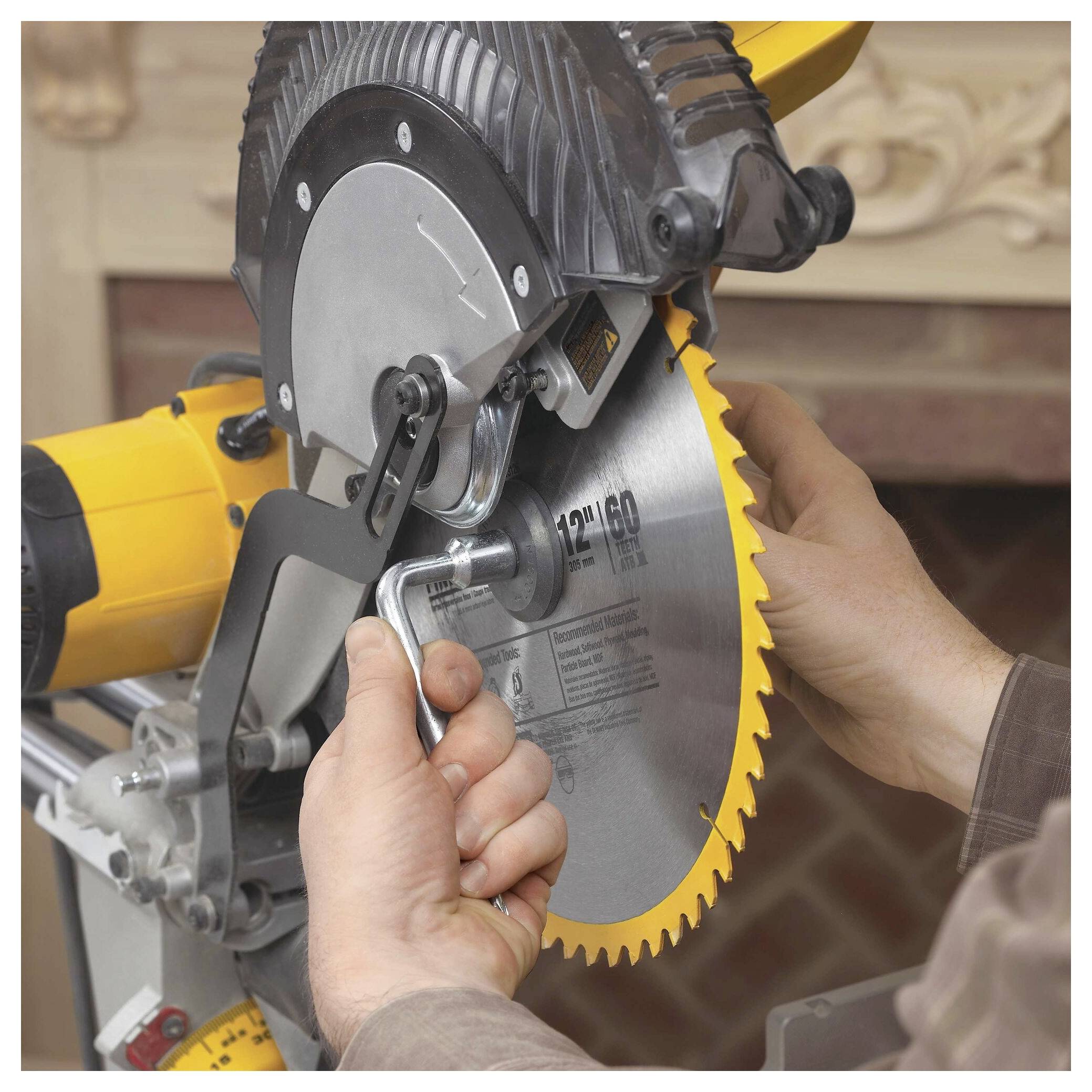 A person tightens a yellow metal saw blade onto a mechanical saw using a wrench, focusing on maintenance or setup in a workshop setting.
