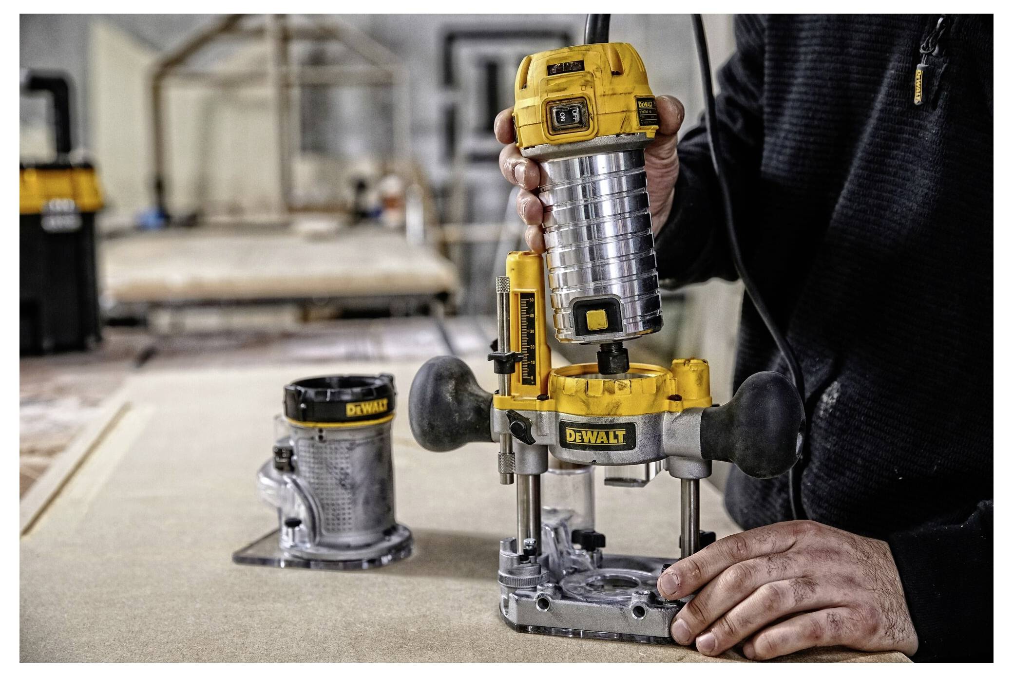 A person demonstrates using a yellow and black plunge router in a workshop, displaying precision and control in a woodworking setting.
