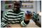 Smiling man in striped shirt holds up a blue USB flash drive toward the camera.