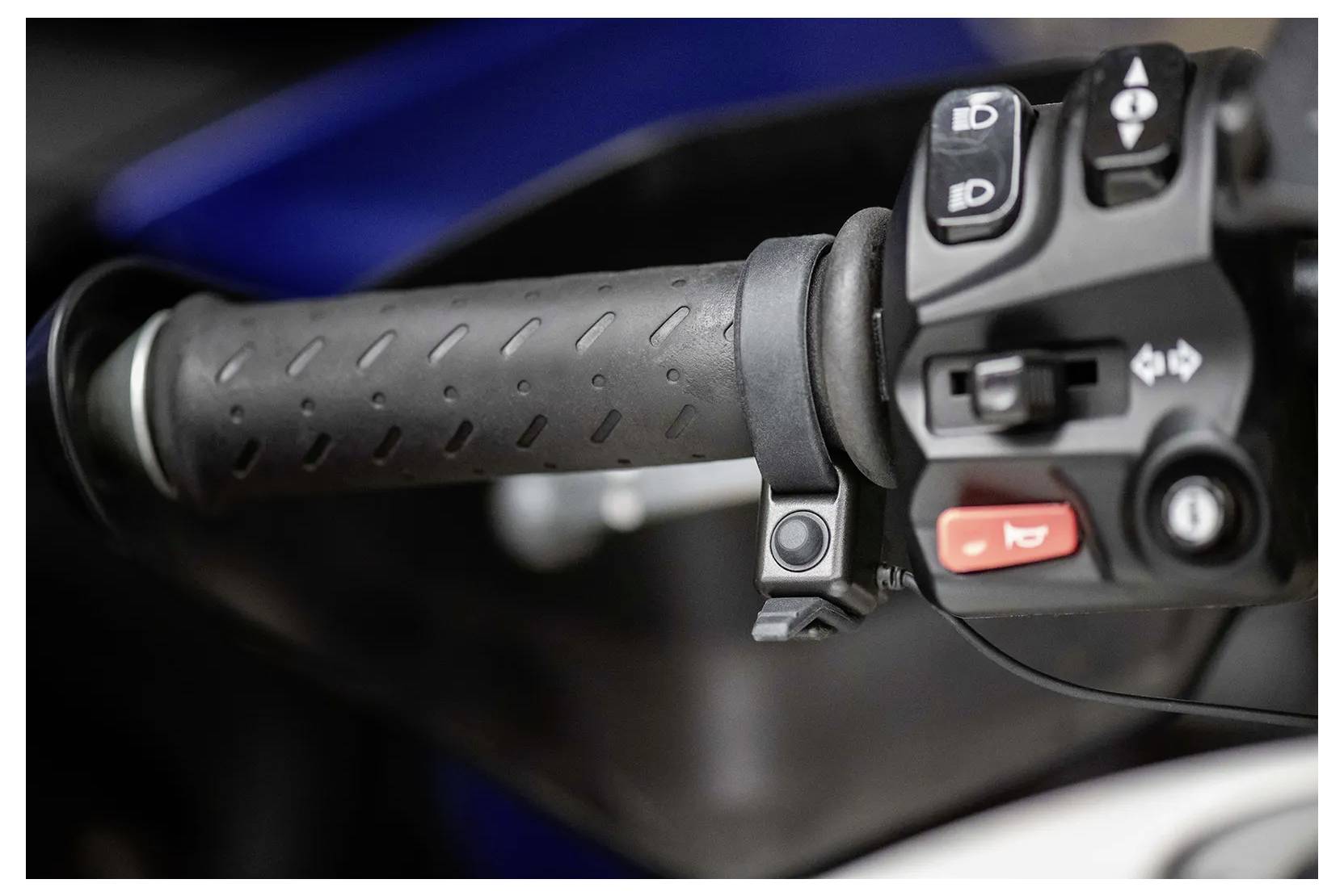 Close-up of a motorcycle handlebar with rubber grip and control buttons.