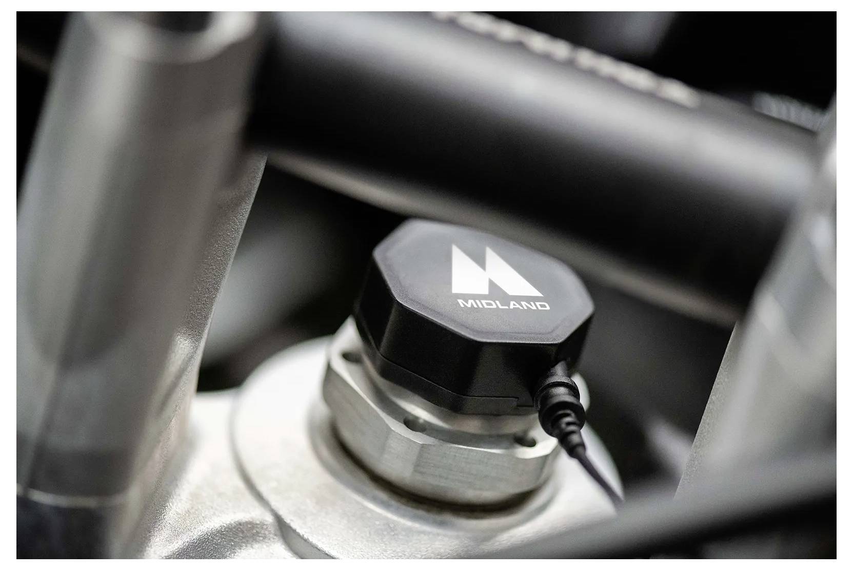 A close-up of a mechanical component with a black cap labeled 'MIDLAND', attached to a metal fitting, possibly part of an engine or machinery.